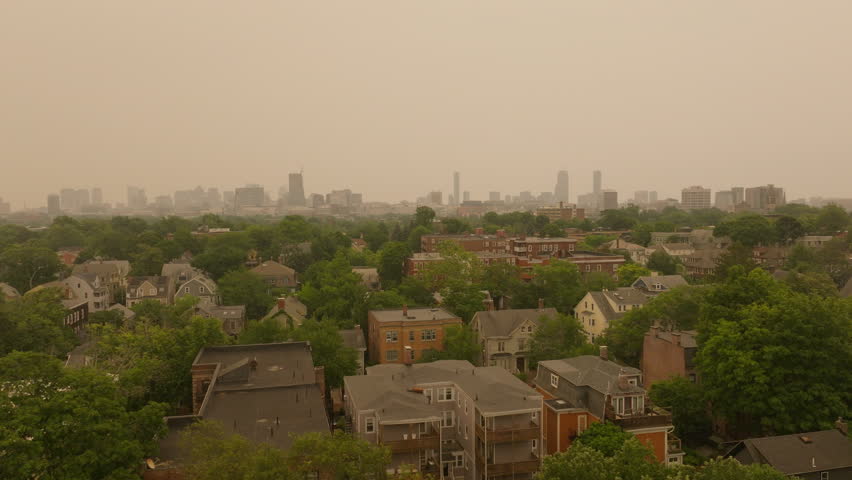 This drone shot shows the smoke from the Canadian wildfires over the Boston, MA, USA skyline. It flies from Cambridge, MA looking toward downtown Boston.