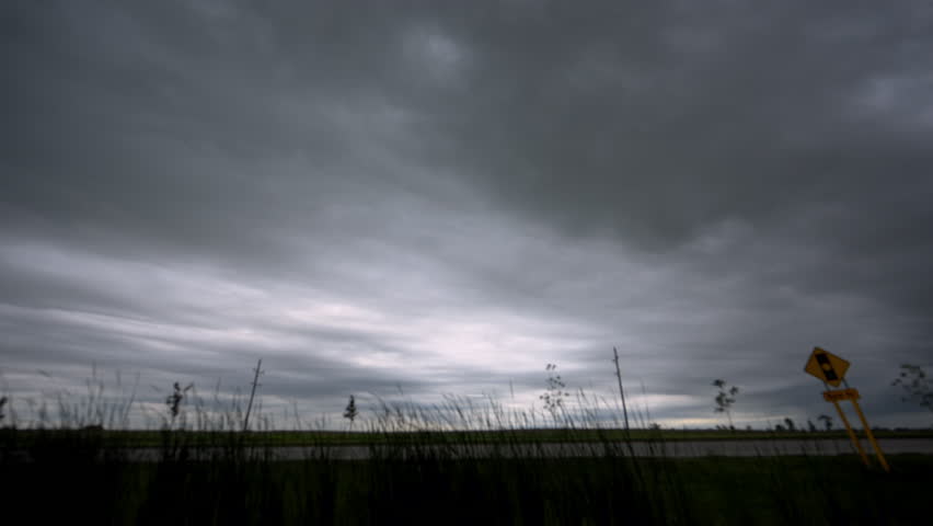 Time lapse of dark storm clouds rapidly moving across the sky before a thunderstorm over a rural landscape.