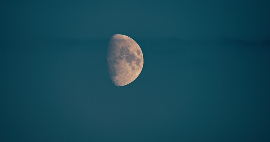 Close Up of a waxing gibbous moon against a clear blue evening sky. Detailed lunar surface visible in a peaceful astronomical night scene.