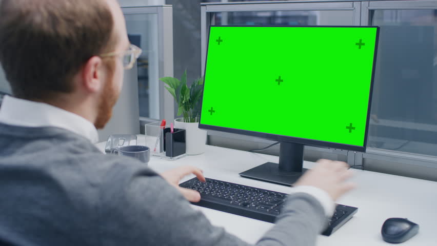 Over the Shoulder Shot of Motivated Businessman Working on Green Screen Chroma Key Desktop Computer in the Big Open Space Office