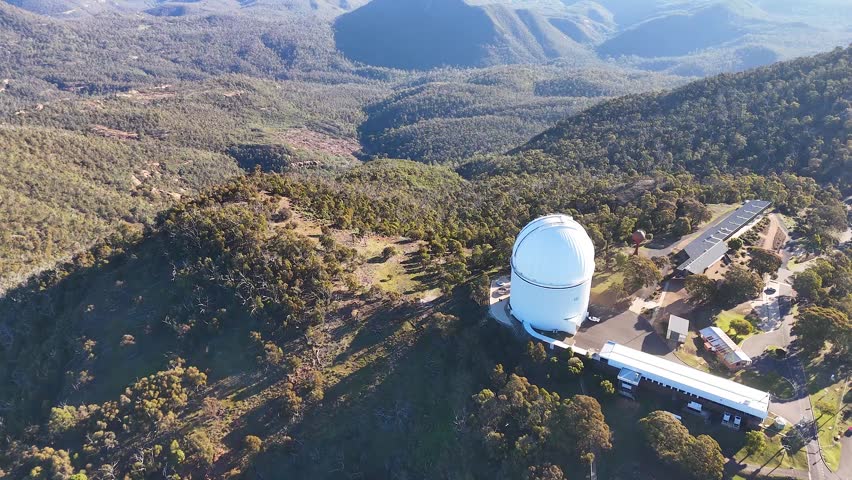 Drone shot of a white telescope dome atop a mountain in Warrumbungle National Park.