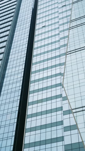 Low angle view looking up at modern glass skyscraper facade against clear sky.