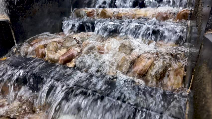 Close up view of water cascading down a multi tiered rock fountain in a garden. slow motion