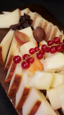 Cheese board with raisins and grapes, served on a wooden tray