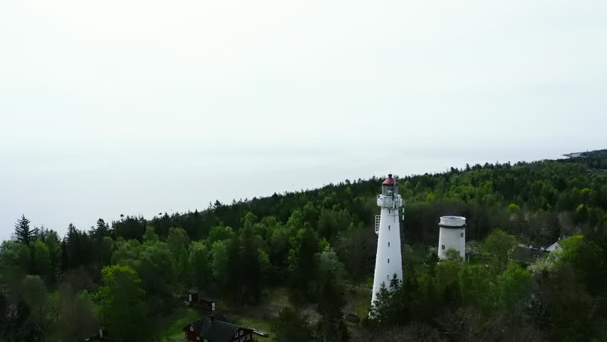 Aerial view of lighthouse on forested peninsula surrounded by water
