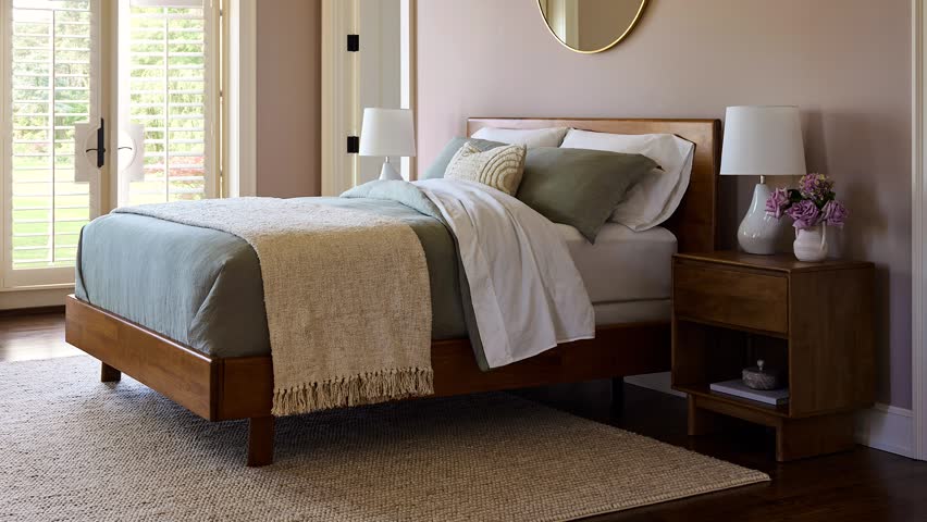 Slow zoom in of a professionally staged farmhouse bedroom featuring a stylish bed and patio doors leading outdoors