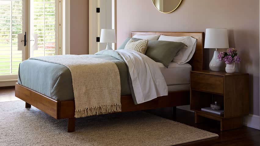 Slow zoom out of a professionally staged farmhouse bedroom featuring a stylish bed and patio doors leading outdoors