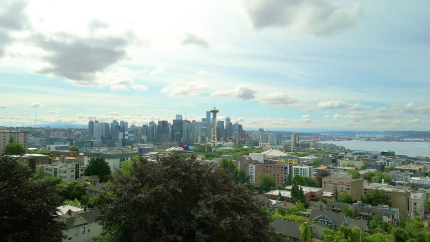 Aerial drone view approaching the Downtown Seattle skyline featuring the Space Needle, modern skyscrapers, and Elliott Bay during daytime in Seattle, Washington, USA.