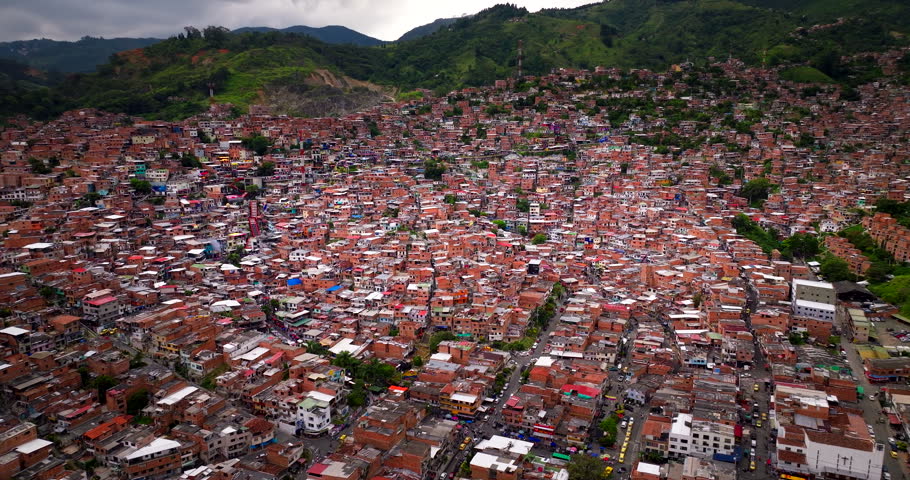 Drone view over sprawling Comuna 13 shantytown built on steep green mountain in Medellin, Colombia. Aerial orbiting