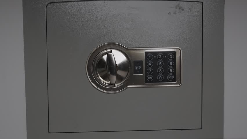 Male hand placing thick bundle of hundred dollar bills inside open metal safe box. Close up on cash savings deposit, wealth protection and financial security storage.