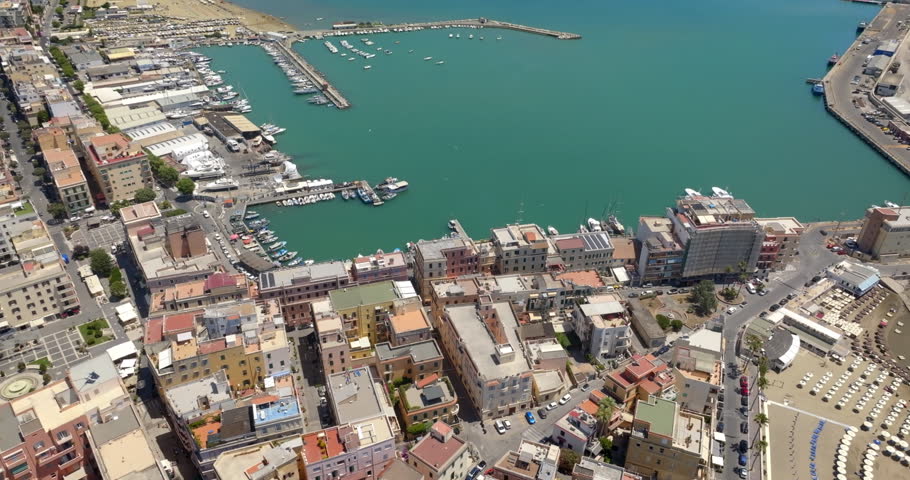 Aerial view of the harbor of Anzio, located in province of Rome, Italy. Panorama from above of a coastal town with vibrant waters, surrounding piers, docks filled with boats in a sunny summer morning.