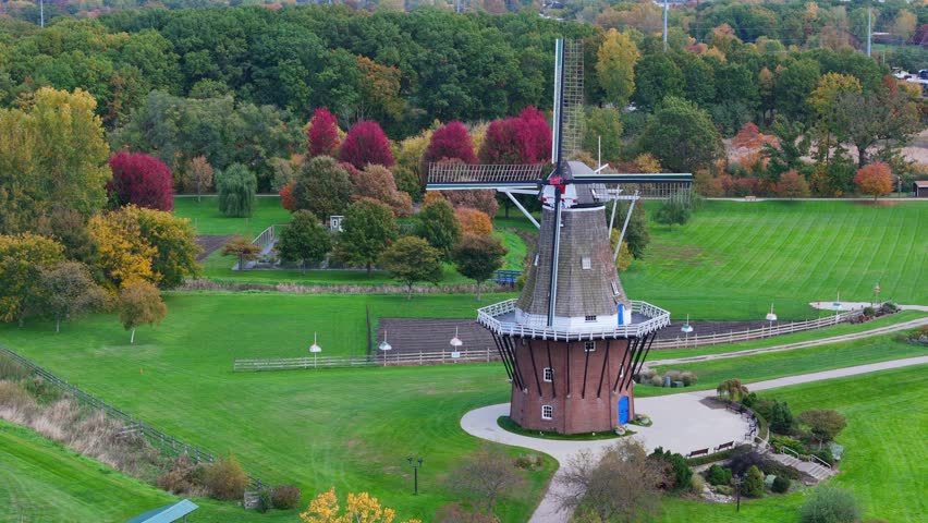 Dutch windmill surrounded by green grass and colorful autumn trees in Holland, Michigan