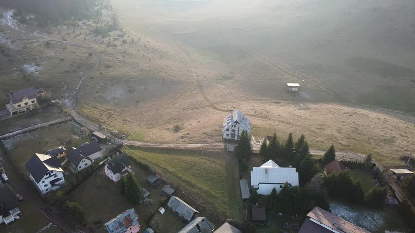 An aerial drone view of the Carpathian Mountains in Romania, showing rolling hills, dense forests, and expansive natural terrain under a clear sky