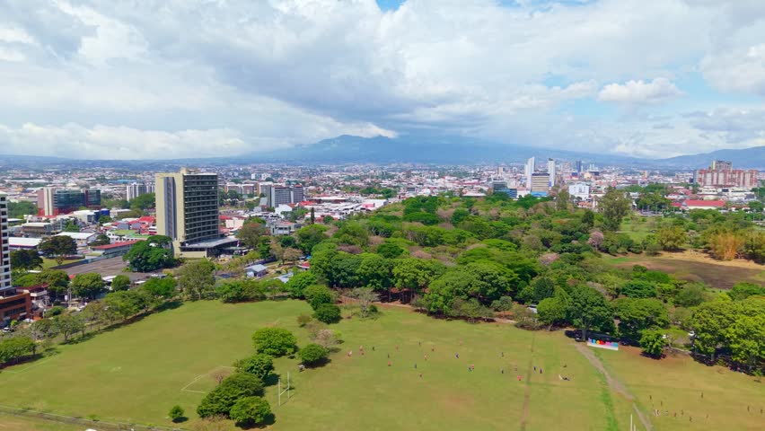 La Sabana metropolitan park with urban skyline and mountains in background in San Jose, Costa Rica. Aerial forward