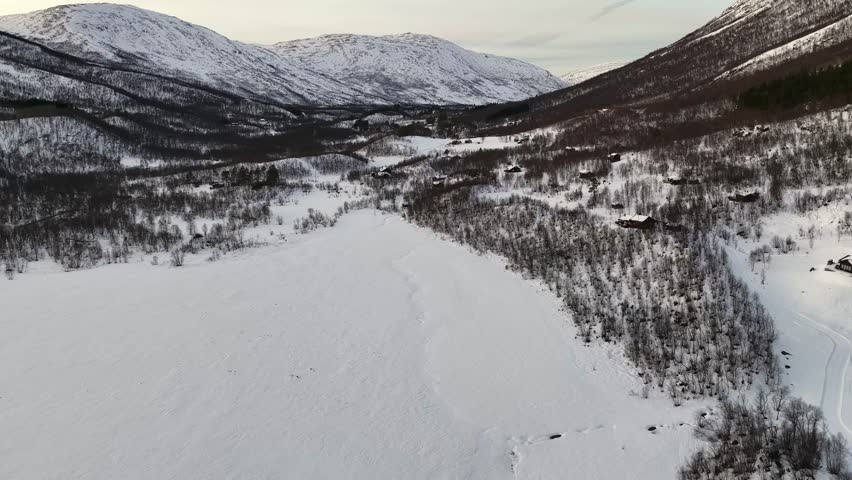 An aerial view of a snow covered winter landscape in Gjora Valley near Sunndalsora, showing forests, hills, and frozen terrain.