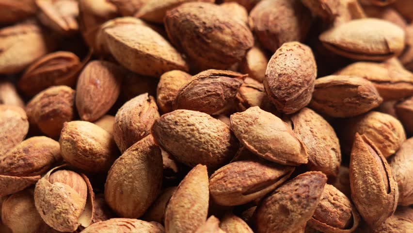 Close-up of roasted almond kernels with cracked shells, rustic texture for healthy snack or baking ingredient