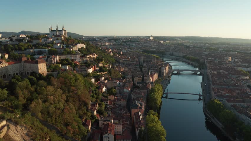 An Aerial cityscape of Lyon with river, bridges, and historic buildings at golden hour, France