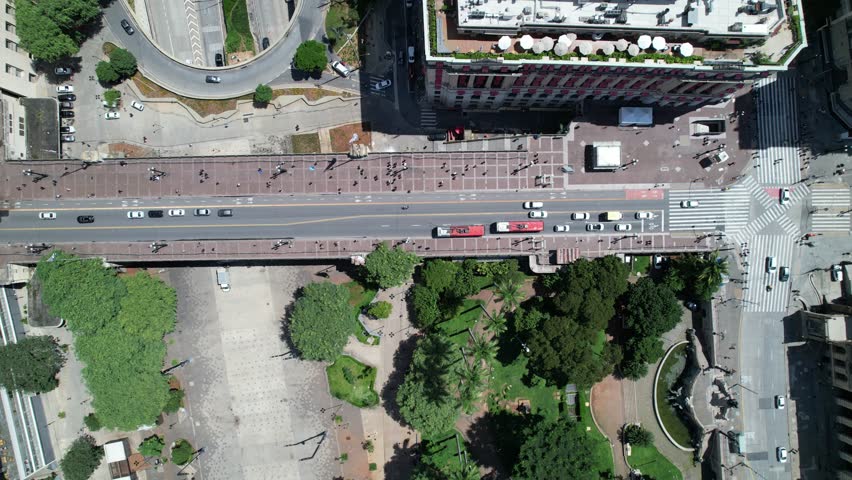 An aerial view shows the core of Sao Paulo with numerous buildings and streets. The city stretches wide under a clear sky with clouds. This view gives a sense of the city