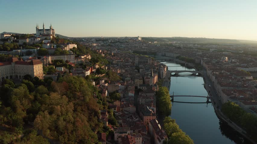 An Aerial cityscape of Lyon with river, bridges, and historic buildings at golden hour, France