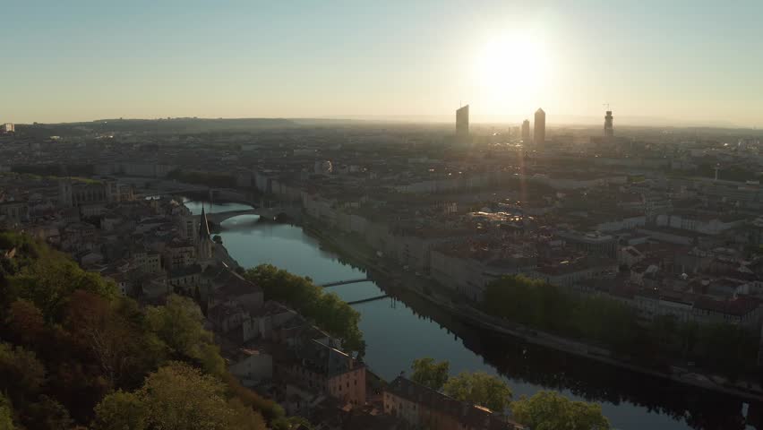 An Aerial cityscape of Lyon with river, bridges, and historic buildings at golden hour, France