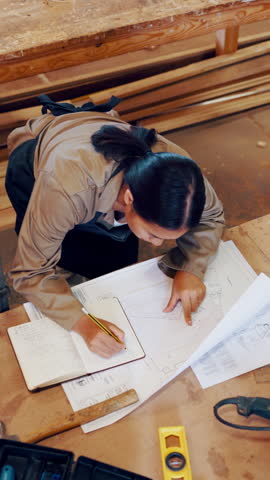 Architecture, woman and writing by blueprint in workshop with wood, notes and layout for process. Above, woodworking and manufacturing in factory for floor plan, project and production for design