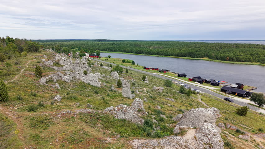 Aerial view of a dramatic limestone formation overlooking a traditional coastal fishing village on Gotland, Sweden, beside the Baltic Sea.