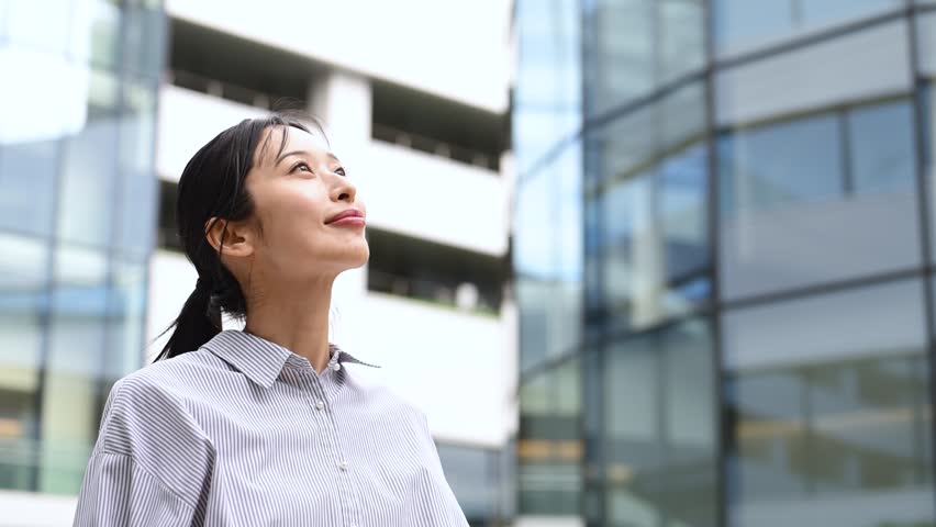 Japanese Businesswoman in Her Thirties Looking Up in an Office District