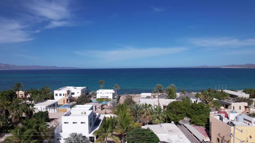 Aerial drone view overlooking a coastal town beside the deep blue waters of Baja California Sur, Mexico.