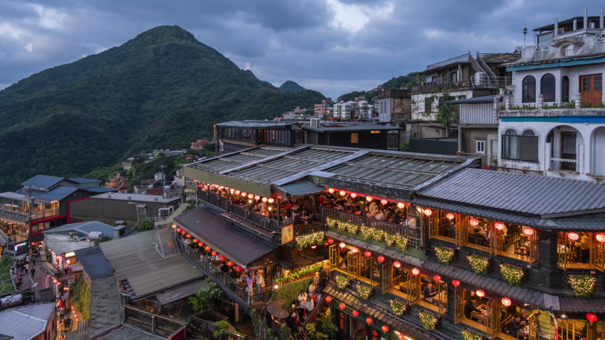 Dusk to night timelapse showing tourists visiting the Jiufen Old Street shops and teahouses, New Taipei City, Taiwan, zooming out.