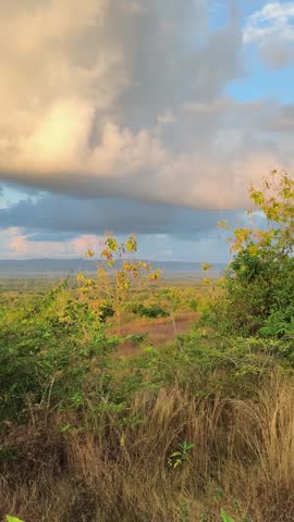 Scenic hill landscape at golden hour with dramatic clouds over the rural savannah field