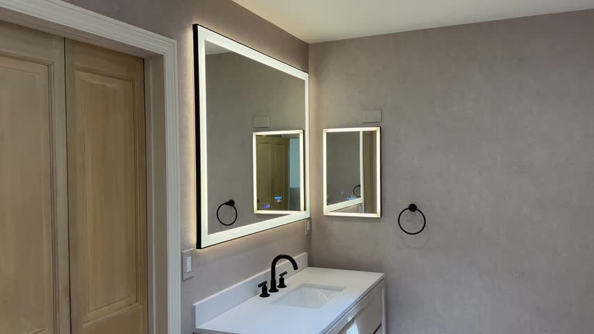 A wide-angle shot of a modern bathroom entrance showing a natural wood door leading to a minimalist bathtub area