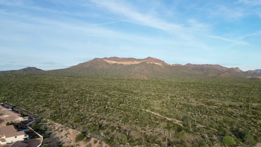 An aerial view of a residential development in the Sonoran Desert showing suburban homes, arid terrain, and distant mountains in Arizona