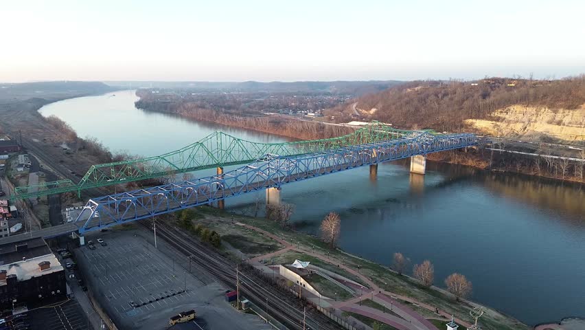 An aerial view of the Ben Williamson Memorial Bridge and the Simeon Willis Memorial Bridge crossing the Ohio River, captured in calm daylight