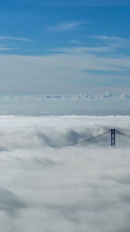 A drone shot of dense clouds over the Tejo Bridge in Lisbon
