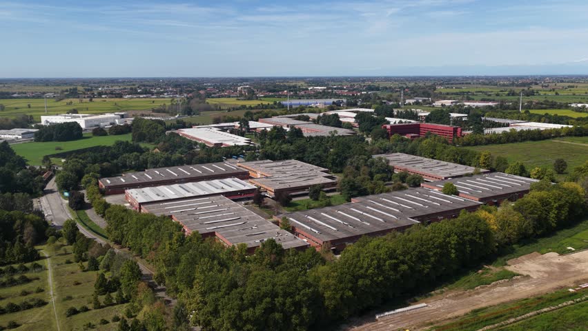 An aerial view of an industrial complex surrounded by trees and fields on the city outskirts in Mazzarrone, Italy.