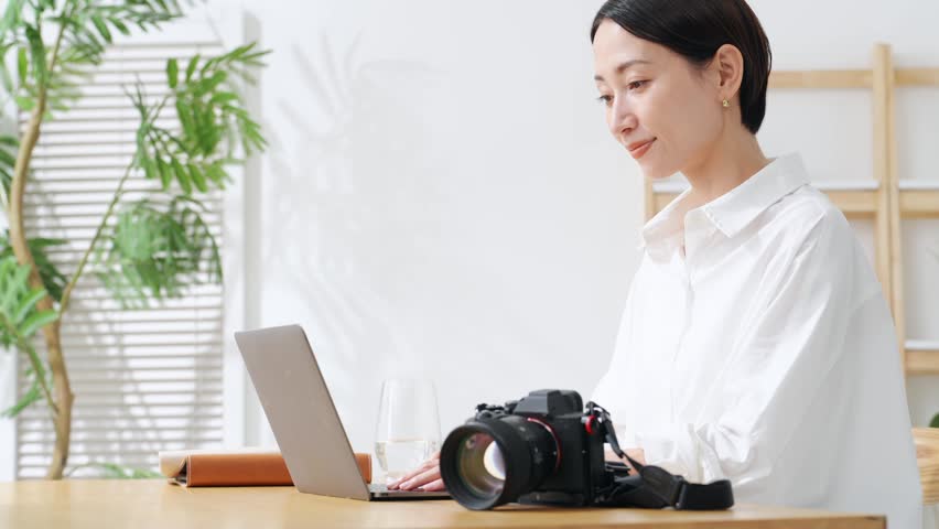 A woman using a camera and a laptop. Photography, editing, shooting, photographer, female photographer, image processing, auctions, listing items.