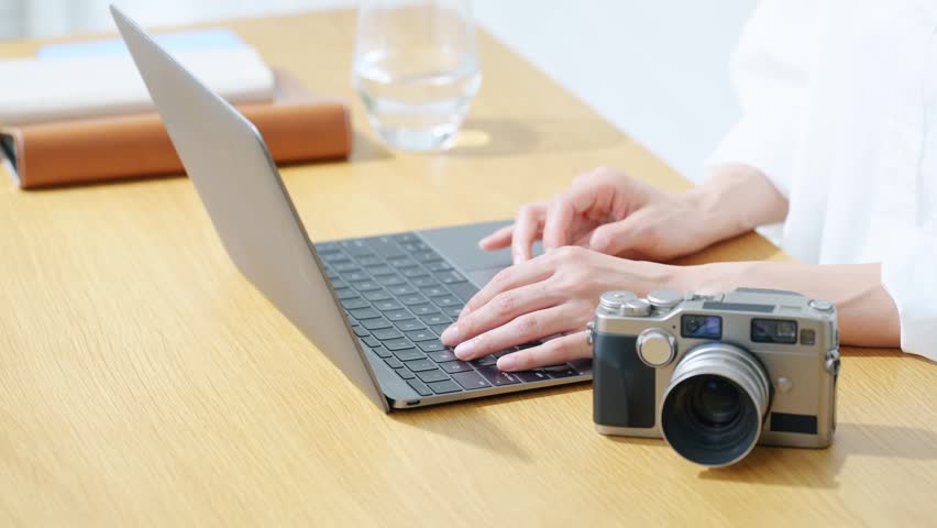 A woman using a camera and a laptop. Photography, editing, shooting, photographer, female photographer, image processing, auctions, listing items.