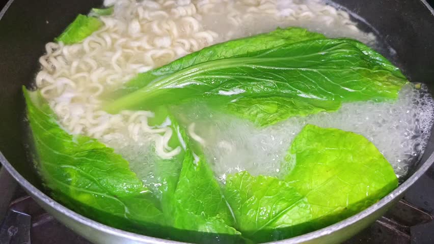 Boiling instant noodles with green vegetables in pan