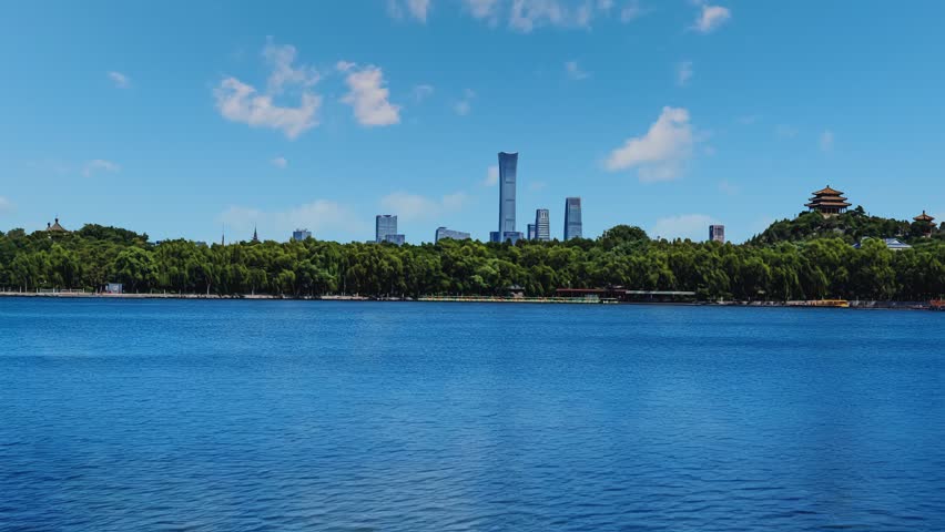 Timelapse of Beijing Beihai Park featuring China Zun skyscraper and CBD skyline with lake reflections and moving clouds.
