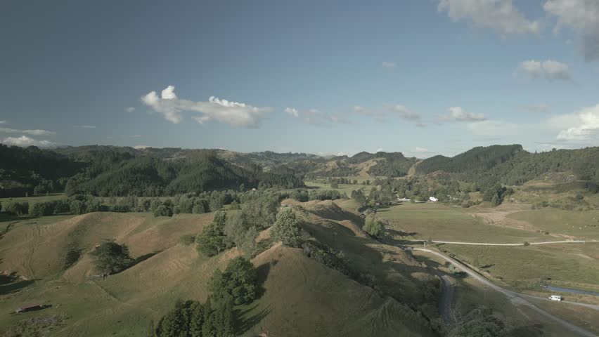 An Aerial view of rolling green hills with winding road and scattered farmland in New Zealand North Island