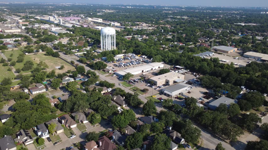 Towering cylindrical water reservoir overlooks commercial warehouse facilities. Prominent municipal infrastructure rises above industrial distribution centers residential blocks, Irving, TX. USA
