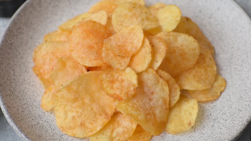 Crispy potato chips, golden slices seasoned with salt and spices. Potato chips as a food background for your design
