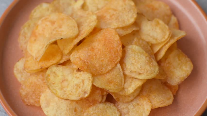 Crispy potato chips, golden slices seasoned with salt and spices. Potato chips as a food background for your design
