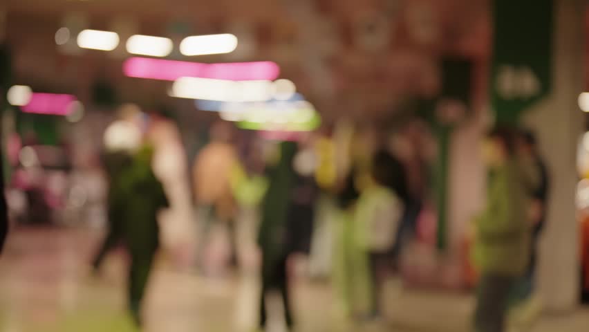 Anonymous crowd of people walking in a shopping mall with beautiful bokeh lights in the background. Unrecognizable shoppers moving through a brightly lit, out-of-focus corridor