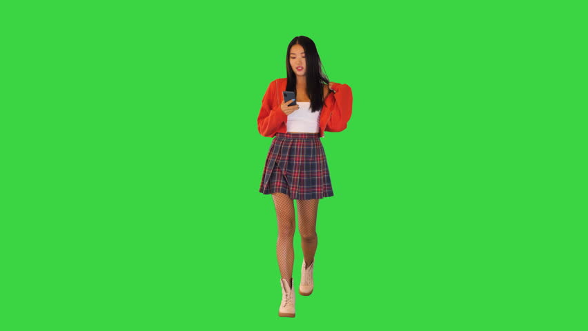 Lighthearted asian girl takes a selfie while walking on a Green Screen, Chroma Key.
