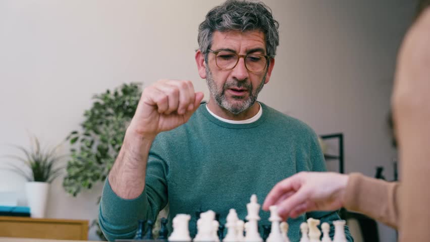 Video of mature man playing chess with a friend at home