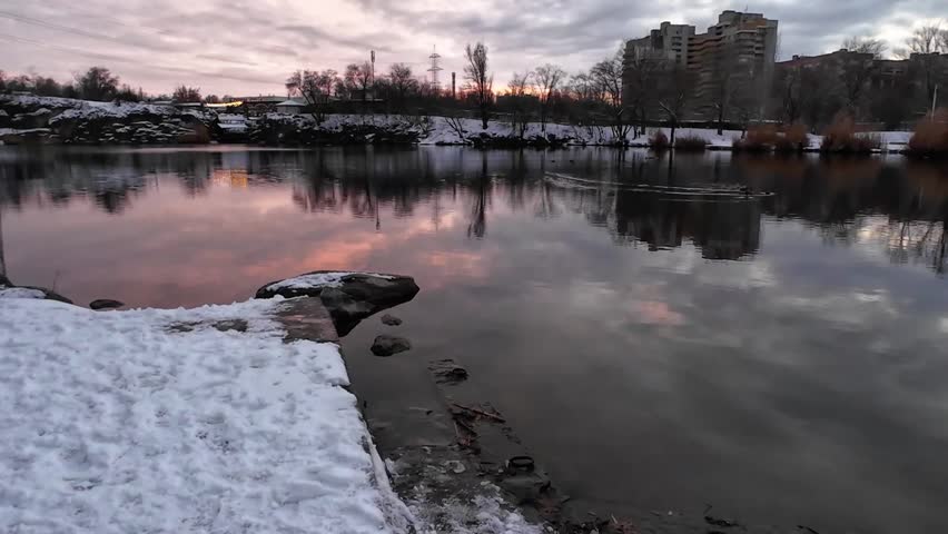 Sunset cumulus sky over a lake in winter in city