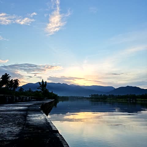 Time-lapse video footage of the sun rising behind hills and a river.