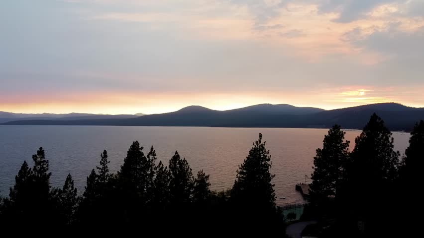 North Lake Tahoe: Drone rises past pines to reveal Lake Tahoe sunset near Kings Beach and Brockway