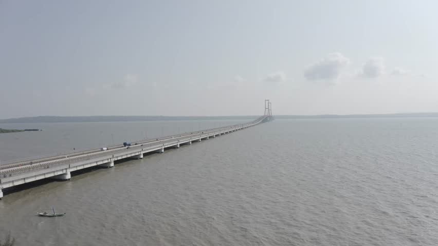 High angle aerial drone shot of Suramadu cable-stayed bridge over Madura strait with traffic in Surabaya, East Java, Indonesia.